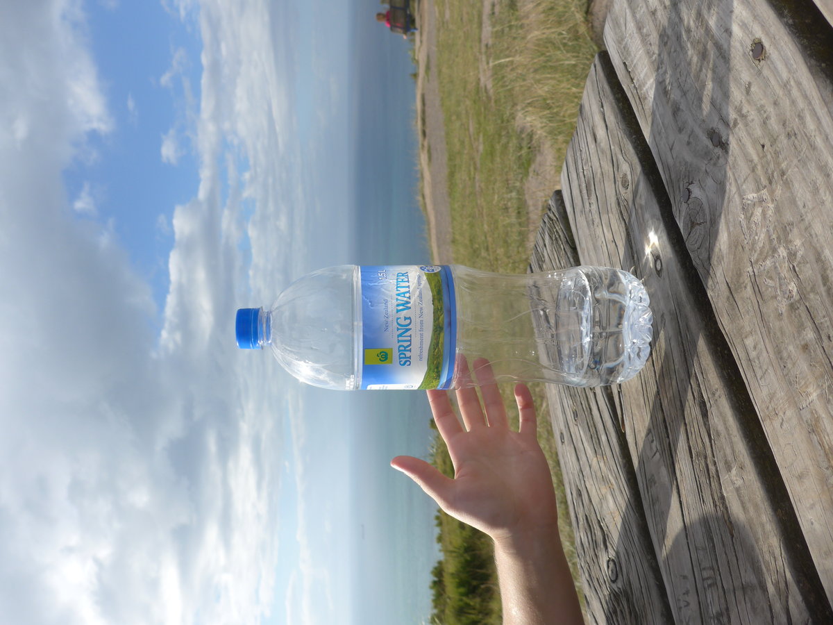 (190'744) - Da kommt eine ausgestreckte Hand zur Flasche mit Wasser am 21. April 2018 auf dem Mount Maunganui bei Mauao