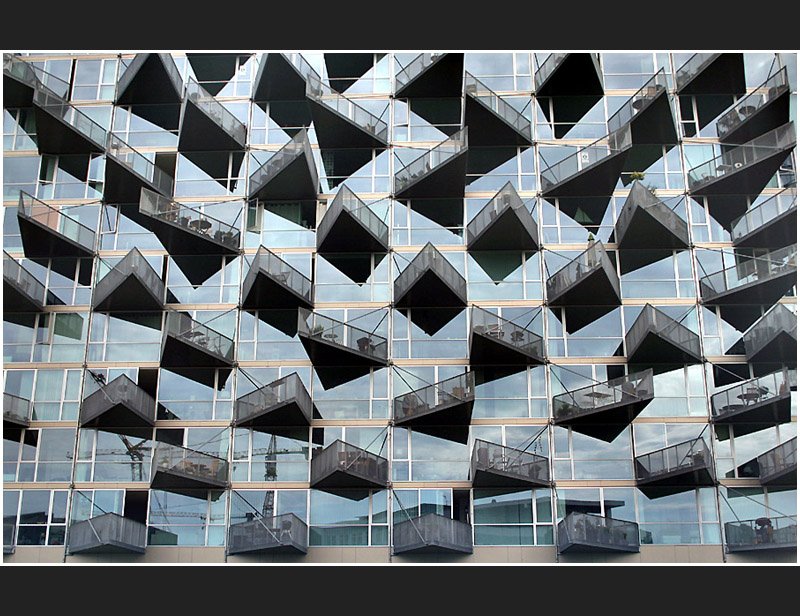 Immer wieder ein fotografisches Thema: Die Fassaden von Wohngeb�uden mit ihren Balkonen. Hier ein sehr eigenwilliges Wohngeb�ude in Kopenhagen. Die Fassade ist v�llig verglast und die dreieckigen Balkone zeigen mit ihren Spitzen in unterschiedliche Richtungen. Im Ausschnitt gesehen ergibt dies ein ungew�hnliches Bild. (Matthias)